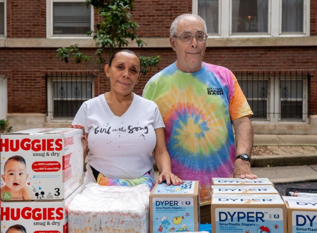 A resident and board member of Voice of the People distribute diapers during the Back2School Summer Bash